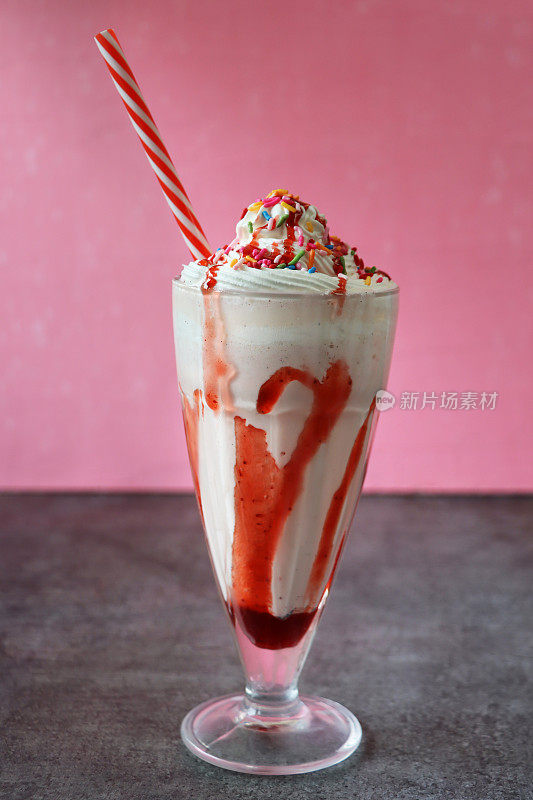 草莓奶昔/冰沙，红色和白色条纹的吸管，粉色的背景，注意前景